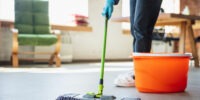 A dedicated Tidy Bird Cleaning house cleaner meticulously mopping and scrubbing the kitchen floor to leave it spotless and refreshed.