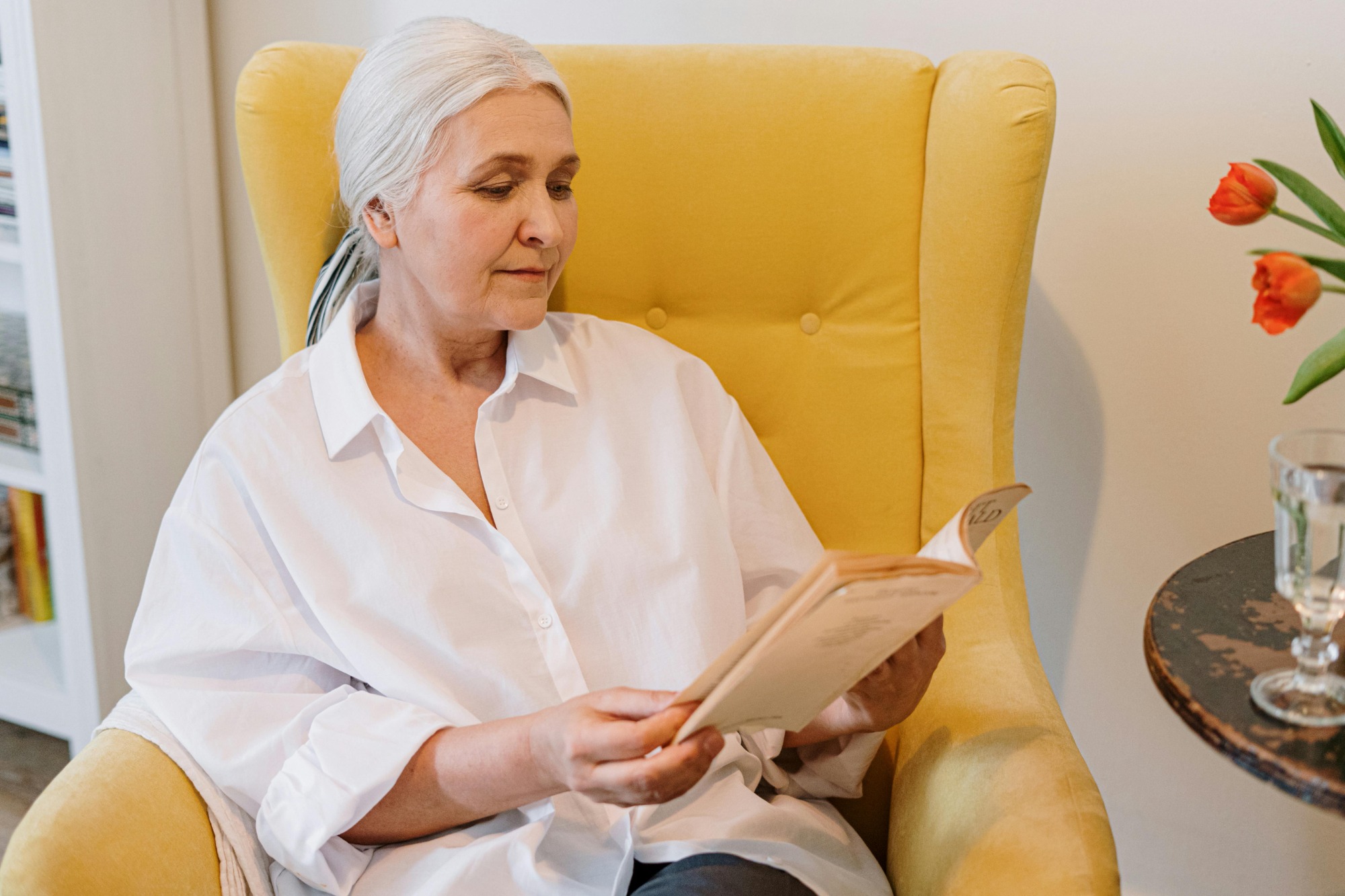 senior woman sitting in yellow chair reading